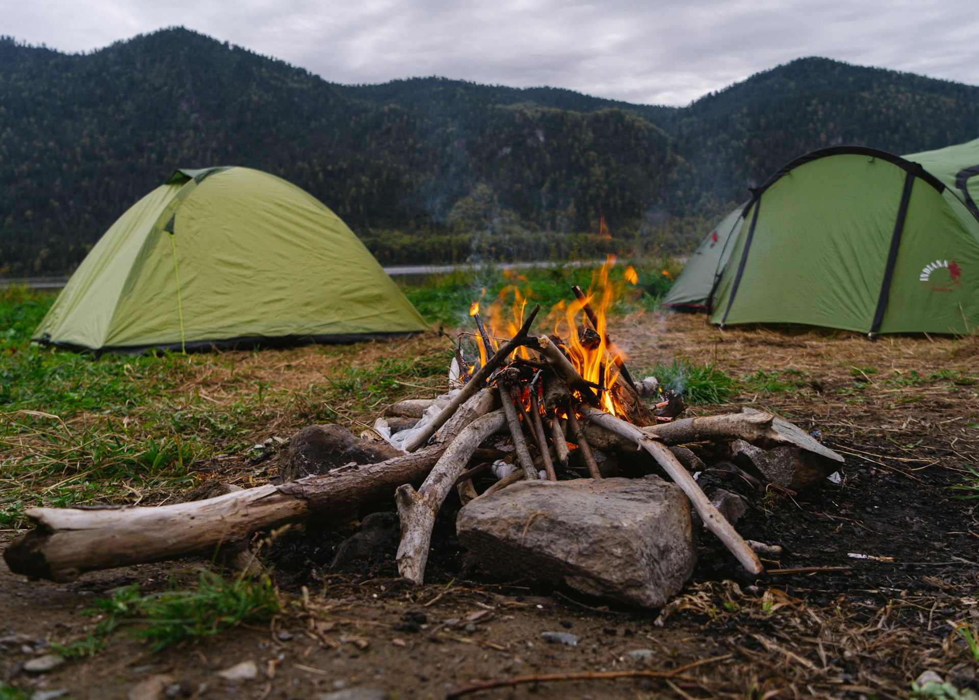 a camp site with a camp fire and tents for Friends group travel deals